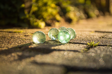 Translucent glass marbles on the sidewalk.
In the light of the setting sun.
Beautiful reflections in the marbles.
