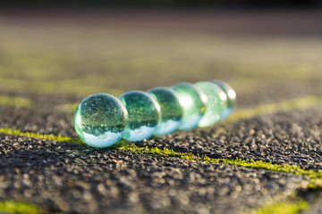Translucent glass marbles on the sidewalk.
Neatly arranged in the light of the setting sun.