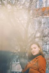 girl in a red jacket and black turtleneck with flowing hair on the background of a blossoming tree in the spring  