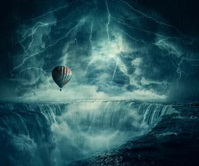 Foto op Canvas StormFall Inspirational imaginary view, scary landscape as a hot air balloon fly over the chasm of a foggy waterfall below a dark stormy sky. © psychoshadow