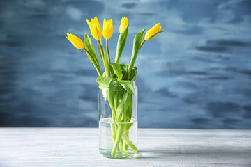 Glass vase with bouquet of beautiful tulips on color background