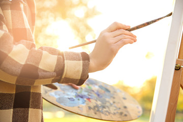 Close up view of female artist painting picture outdoors