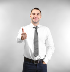 Handsome man showing thumb up sign, on light background