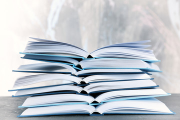Stack of open books on light background