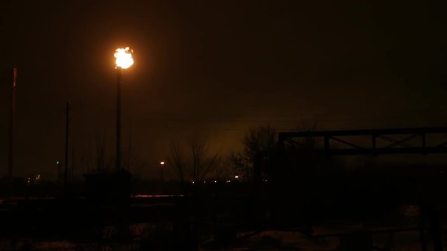 Gas flare burns at an oil refinery at the night