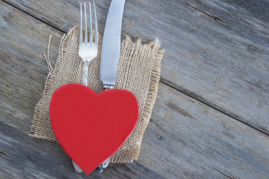 valentine's day concept/cutlery and red heart on sackcloth and old wooden background