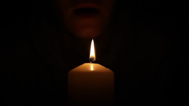 Woman blows out the candle in the dark
