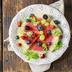 Appetizer of juicy watermelon, ripe blackberry and fresh blueberries on a black stone chilled board. The concept  healthy natural foods. Top view. selective Focus
