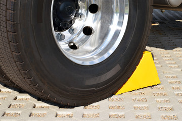 Yellow chock at the wheel of a parked truck 