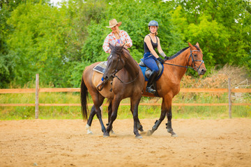 Obraz premium Cowgirl and woman jockey riding on horses