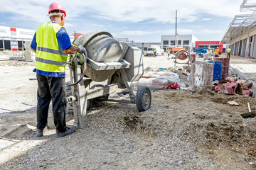 Cement mixer machine and wheelbarrow at building site