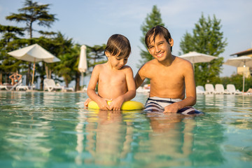 Fototapeta na wymiar Young boy kid child splashing in swimming pool having fun leisur