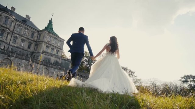 Wedding Couple Runing On Sunset Before Old Castle