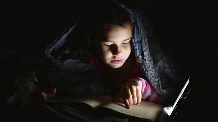 teen reading girl child reads book reading at night with flashlight lying under blanket