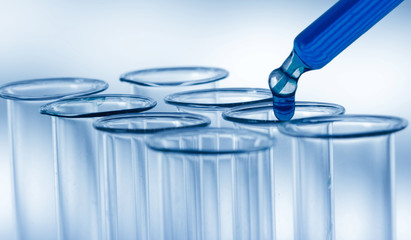 Pipette adding fluid to one of several test tubes .medical glassware