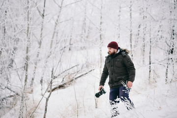 Fototapeta na wymiar Traveler photographer taking pictures in the winter forest