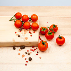 Cherry tomatoes on wooden kitchen board with spices