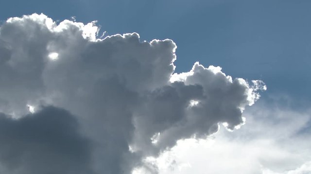 4K time lapse of sunlight dancing behind large cloud as sun burns through revealing bright white light.