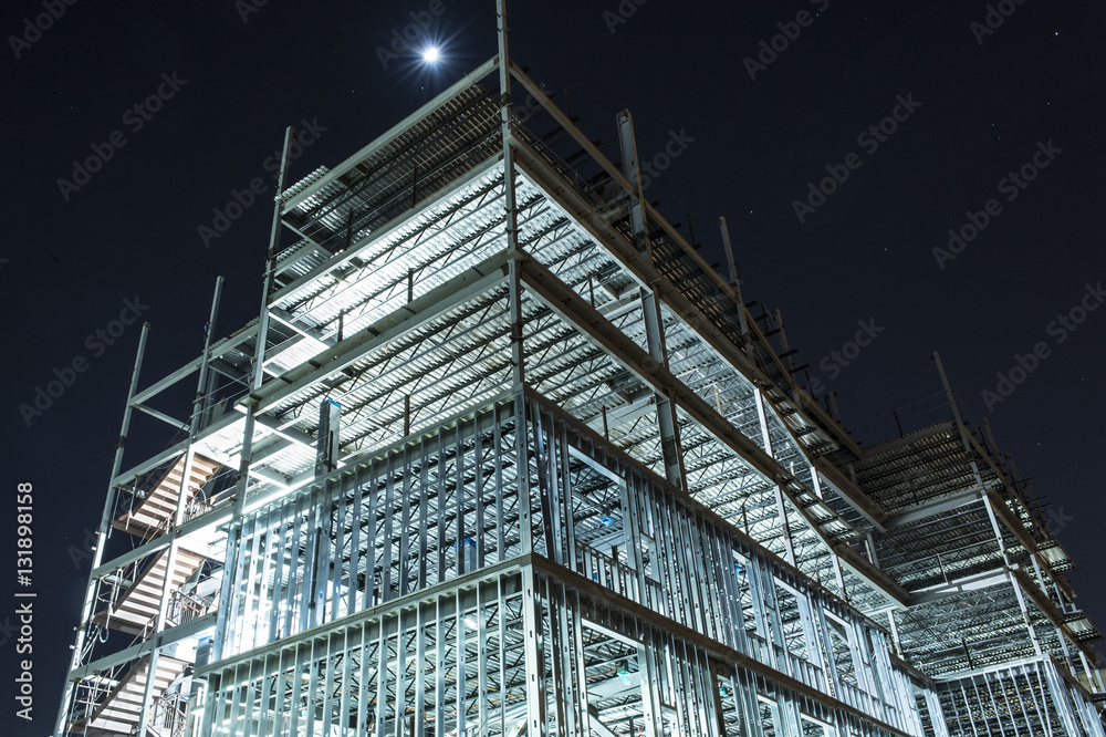 Wall mural metal framed multi floor building under construction illuminated at night