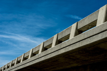 highway overpass bridge view from below against a blue sky and white clouds