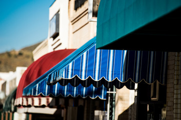 colorful awnings on adjoining small shops - obrazy, fototapety, plakaty