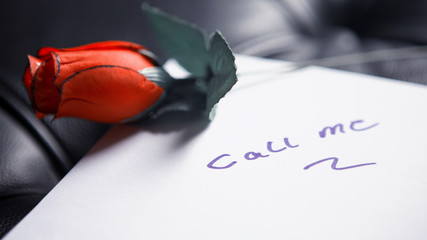 Call Me written on paper with red rose