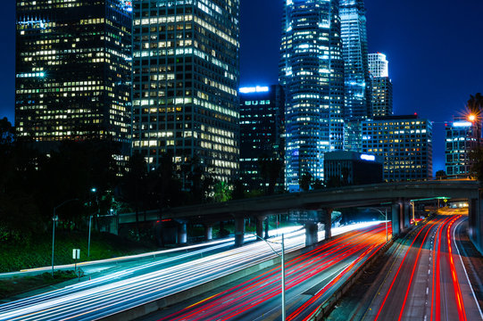car lights streaking on freeway with high rise buildings at night in Los Angeles