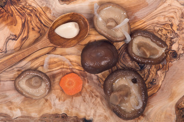 Shiitake marinated mushrooms with wooden spoon on olive wood cutting board