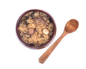Traditional sour cabbage soup in ceramic bowl with wooden spoon isolated on white background