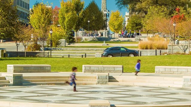Tilting up to Asheville NC Pack Square Park on a Sunny Autumn Morning with Children Running Around and Ending with Fall Colored Foliage and Landmarks in Front of a Blue Sky