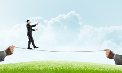 Business concept of risk support and assistance with man balancing on rope