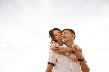 Couple in love, young man and woman hugging on white sky background, happy couple looking at copy space. Lifestyle concept