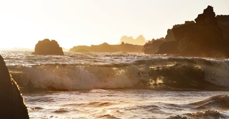 Wave Crashing on Rugged Shore at Sunset - 131901792