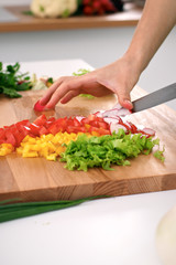 Close up of  woman's hands cooking in the kitchen. Housewife slicing ​​fresh salad. Vegetarian and healthily cooking concept