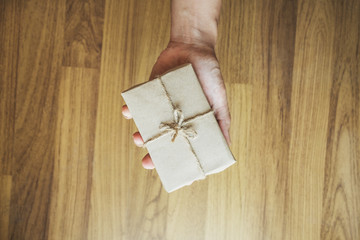 A man hand holding gift box on hand, on white wood background