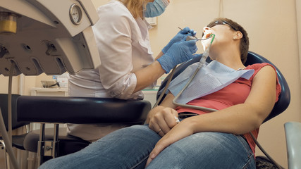 Fototapeta premium Woman at the dentist clinic office gets dental medical examination and treatment. Odontic and mouth health is important part of modern human life that dentistry help with.