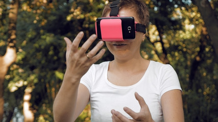 Young woman explores virtual reality using VR glasses. Augmented reality quickly comes into human everyday life. VR helmet and glasses are the most popular devices for playing games and enjoying AR.