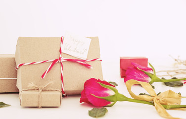 Valentines gift preparation, parcel gift box with roses and leaves, on white table