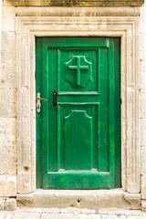 Old wooden green door with Christian cross in Kotor, Montenegro.