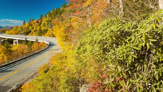 A Scenic View Panning Towards Linn Cove Viaduct against Grandfather Mountain on the Blue Ridge Parkway near Linville NC with Fall Colored Trees and the Layered Smoky Mountains topped by a Blue Sky