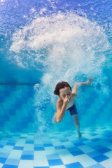 Funny portrait of boy swimming and diving in blue pool with fun - jumping deep down underwater with splashes and foam. Family lifestyle and summer children water sports activity with parents.   © Tropical studio