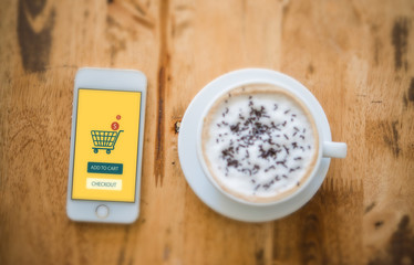 Top view - Smart phone online shopping. Desk with coffee in back