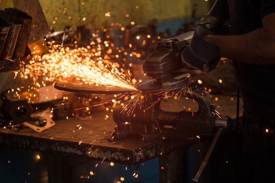 Close up of worker using an angle grinder in factory