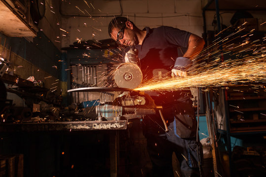 Worker using angle grinder in factory