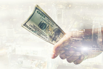Double exposure of Businessman with money in hand with cityscape