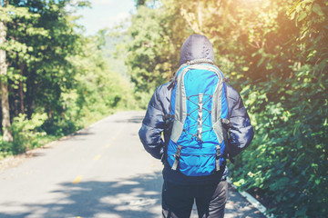 Rear of hiker man walking on the rural road on vacation. Holiday