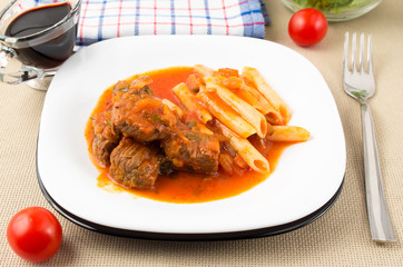 White plate with beef goulash with penne pasta