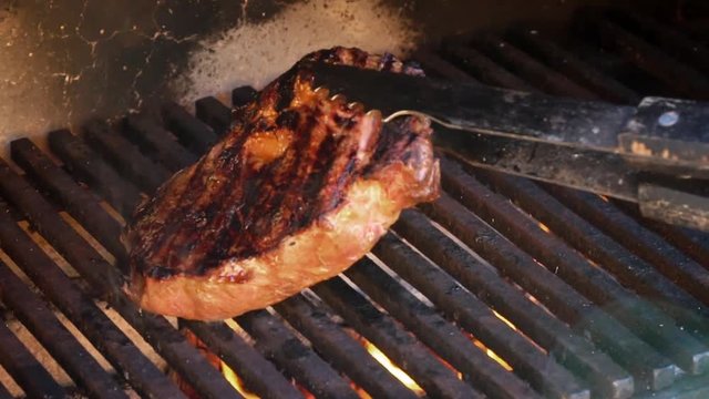 Ribeye steak roasted on the grill barbecue. Slow motion. 120 fps.