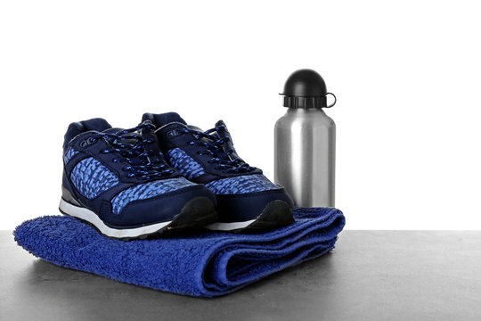 Sport shoes, towel and bottle on table