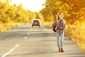 Young woman with backpack on road